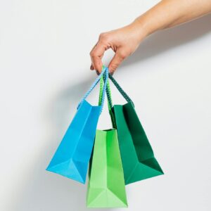 A hand holding vibrant paper shopping bags, perfect for retail and sales themes.
