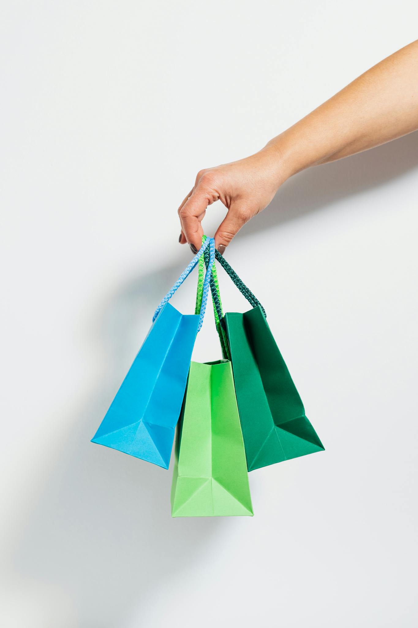 A hand holding vibrant paper shopping bags, perfect for retail and sales themes.