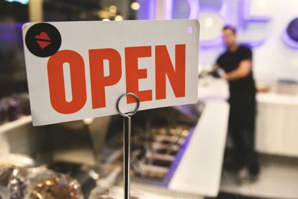 A vibrant open sign in a Los Angeles shop with a blurred figure in the background.