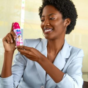Smiling woman holding a baby care product indoors, showcasing happiness.